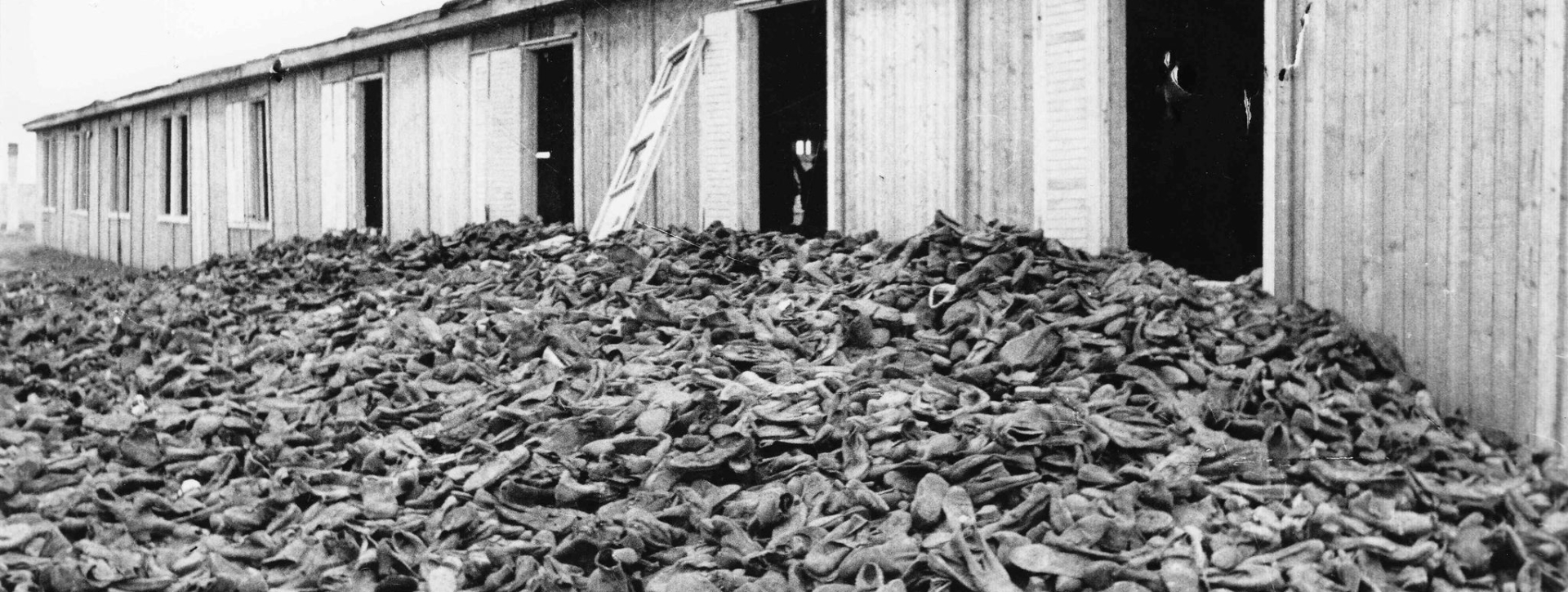 Stosy butów obok baraku z 9 oknami 