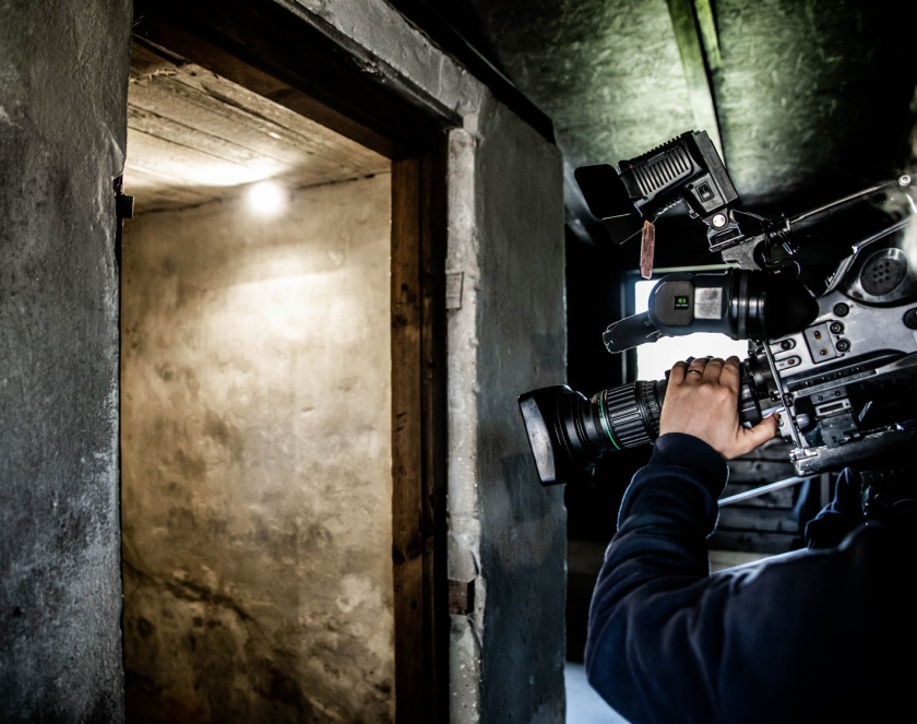 A man with a camera films a concrete bunker.