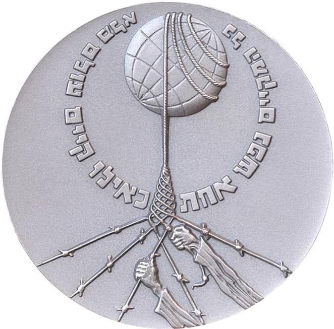 Okrągły, metalowy medal w języku hebrajskim, ręce chwytające drut kolczasty  okalający kulę ziemską 
