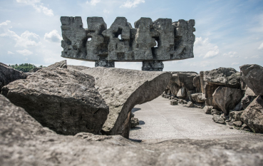 Pomnik Brama; monumentalna betonowa abstrakcyjna budowla, na pierwszym planie bloki kamieni 