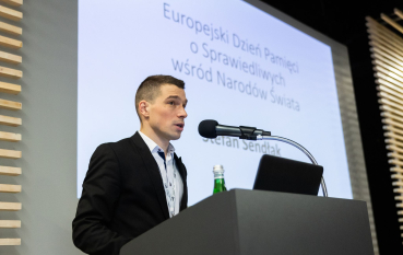 40- letni mężczyzna w garniturze, w tle napis: Europejski Dzień Pamięci o Sprawiedliwych wśród Narodów Świata, Stefan Sendłak 