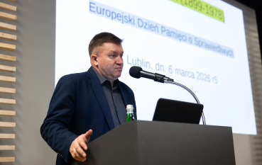 Mężczyzna w średnim wieku stojący przy mównicy 