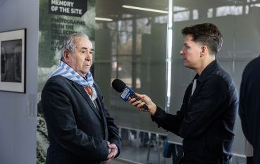 Starszy mężczyzna z chustą w biało niebieskie pasy udziela wywiadu dla młodego dziennikarza TVP 3 Lublin