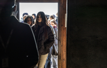 Grupa młodzieży wchodzi do baraku więźniarskiego 