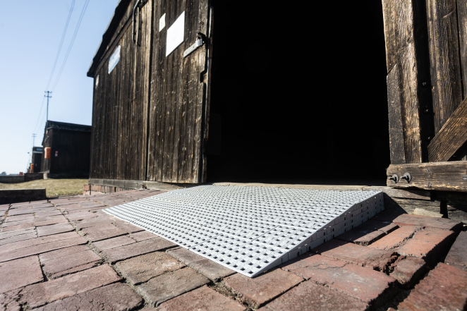 Kratkowany podest pod drzwiami drewnianego baraku. 