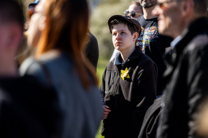 Chłopiec w kaszkiecie z przypiętym do ubrania papierowym żonkilem. 