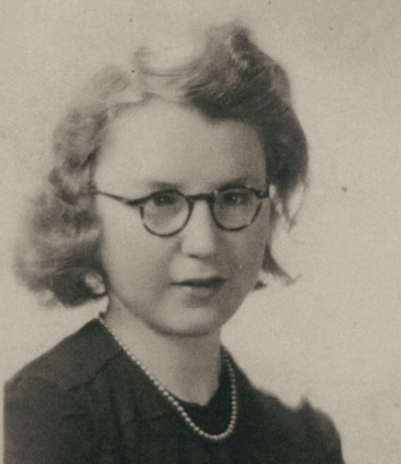Black-and-white portrait photograph of a young woman in a close-up frame. Her hair is neatly combed, and she looks toward the camera. The background is light.