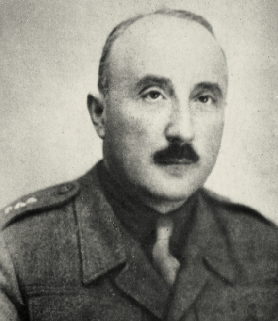 Black-and-white portrait photograph of a man, framed from the chest up. He has short hair and faces the camera. He is wearing formal clothing. The background is neutral.