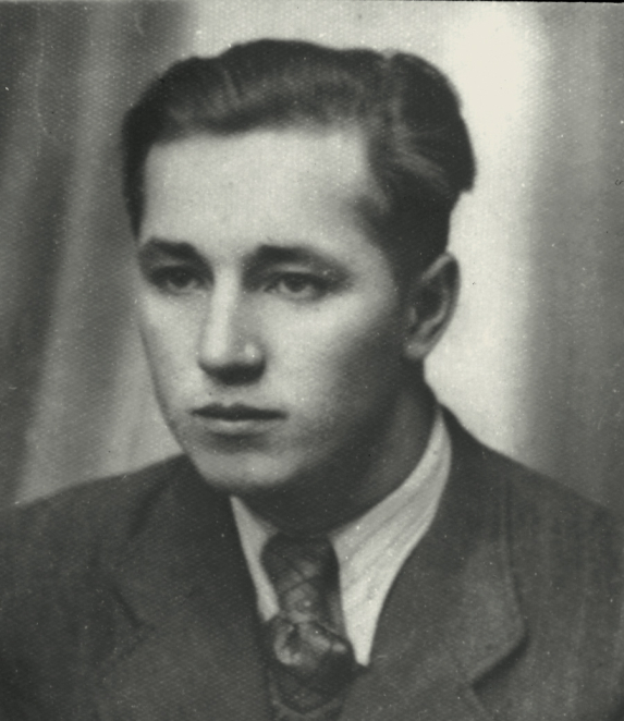 Black-and-white portrait photograph of a young man, framed from the shoulders up. He has short hair and looks straight at the camera. He is wearing simple clothing. The background is neutral.