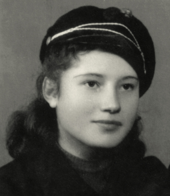 Black-and-white portrait photograph of a young person in a close-up frame. The hair is short or tied back, and the face is directed toward the camera. The background is light and without details.