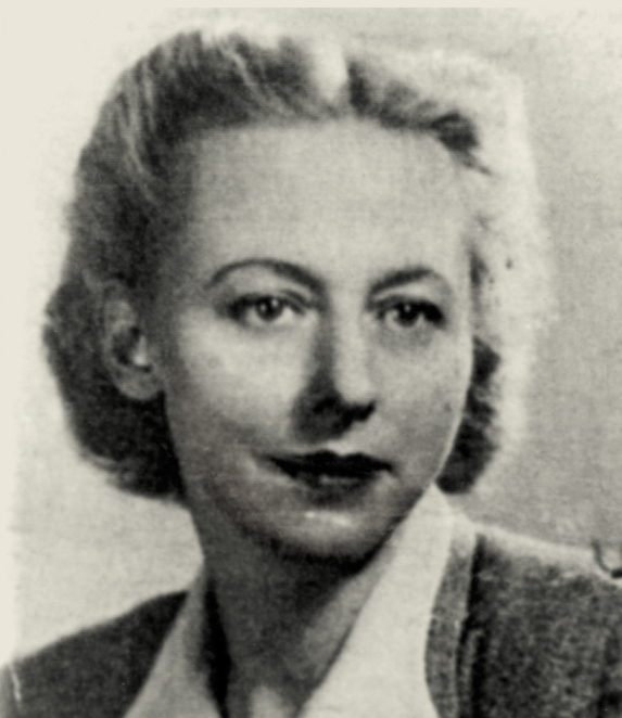 A black-and-white portrait photograph of a woman, shot from the shoulders up. Her hair is short or tied back, and her face is turned slightly away. She is wearing dark clothing. The background is plain.