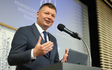 Mężczyzna w garniturze przemawia do mikrofonu.