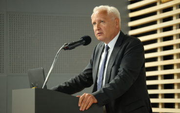 Mężczyzna w garniturze przemawia do mikrofonu.