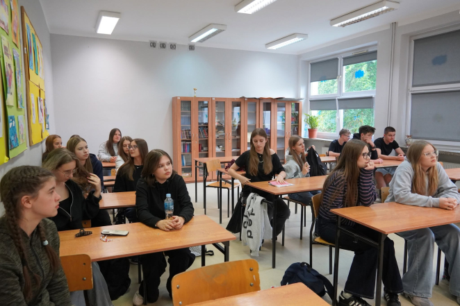 Grupa uczniów siedzących w ławkach szkolnych