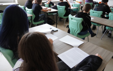 Grupa uczniów siedzących w ławkach szkolnych