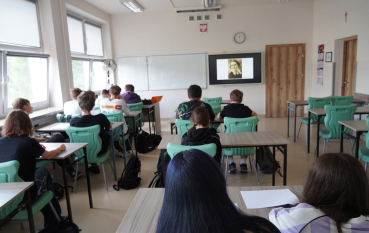 Grupa uczniów siedzących w ławkach szkolnych